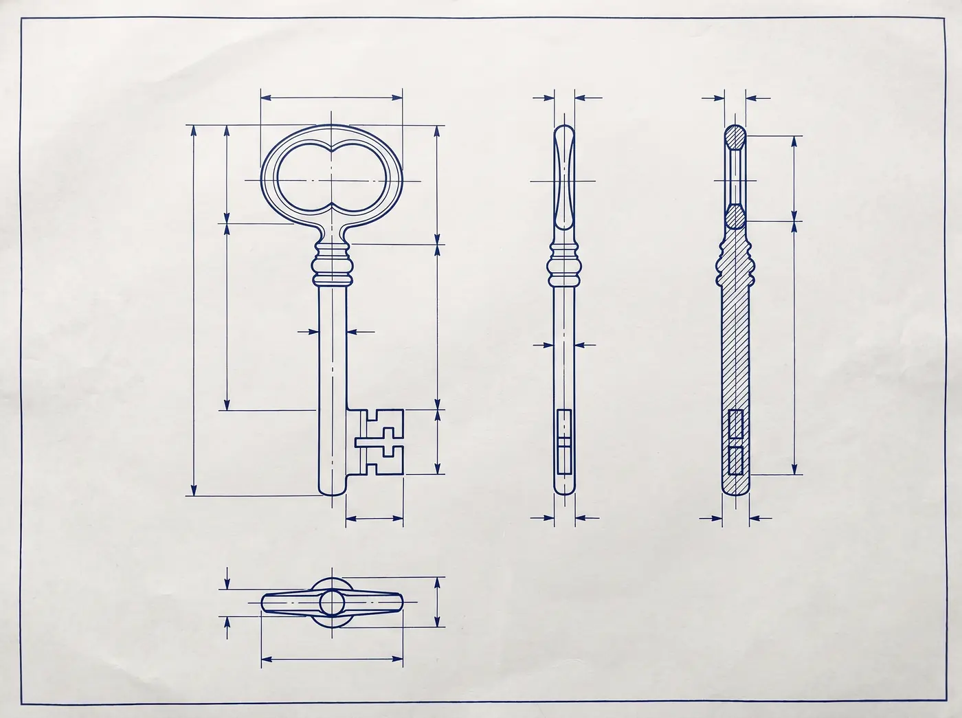 A technical drawing in navy ink on white drafting paper: one large key shown in front, side and top views with a hatched section view.