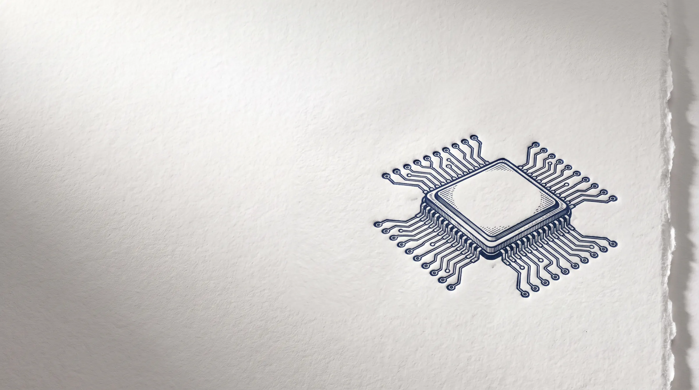 A letterpress print: a microchip and its circuit traces pressed in deep navy ink into thick white cotton paper with a deckled edge, lit from the side so the impression casts a soft shadow.